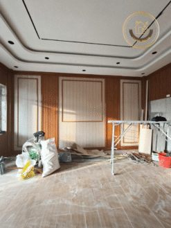 Chính diện mảng tường trung tâm: pano ốp nano sáng, hai dải gương dọc, trần giật cấp lỗ đèn downlight – công trình anh Hoàng.