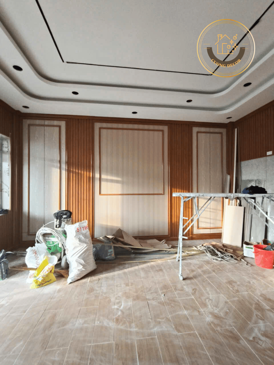 Chính diện mảng tường trung tâm: pano ốp nano sáng, hai dải gương dọc, trần giật cấp lỗ đèn downlight – công trình anh Hoàng.